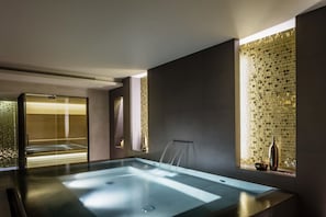 Relax in a serene spa room with a glass-enclosed hot tub and minimalist design.