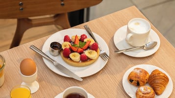A breakfast table with various food items, a teapot, cups, and utensils.