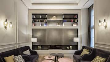 Una sala moderna con sofás oscuros, mesas de centro redondas y una estantería con objetos decorativos.