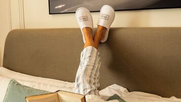 A person lying on a bed with a book, wearing white slippers, and a green pillow is visible.