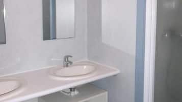 Une salle de bain moderne avec deux lavabos, un miroir et une douche.