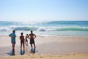 A beach scene with people standing and watching the ocean. - Village Vacances Le Junka (Vieux-Boucau-les-Bains)