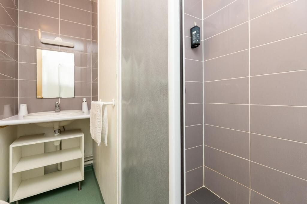 A bathroom with a white sink, mirror, and shelves.