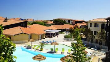 A rooftop swimming pool with lounge chairs and umbrellas, surrounded by residential buildings.