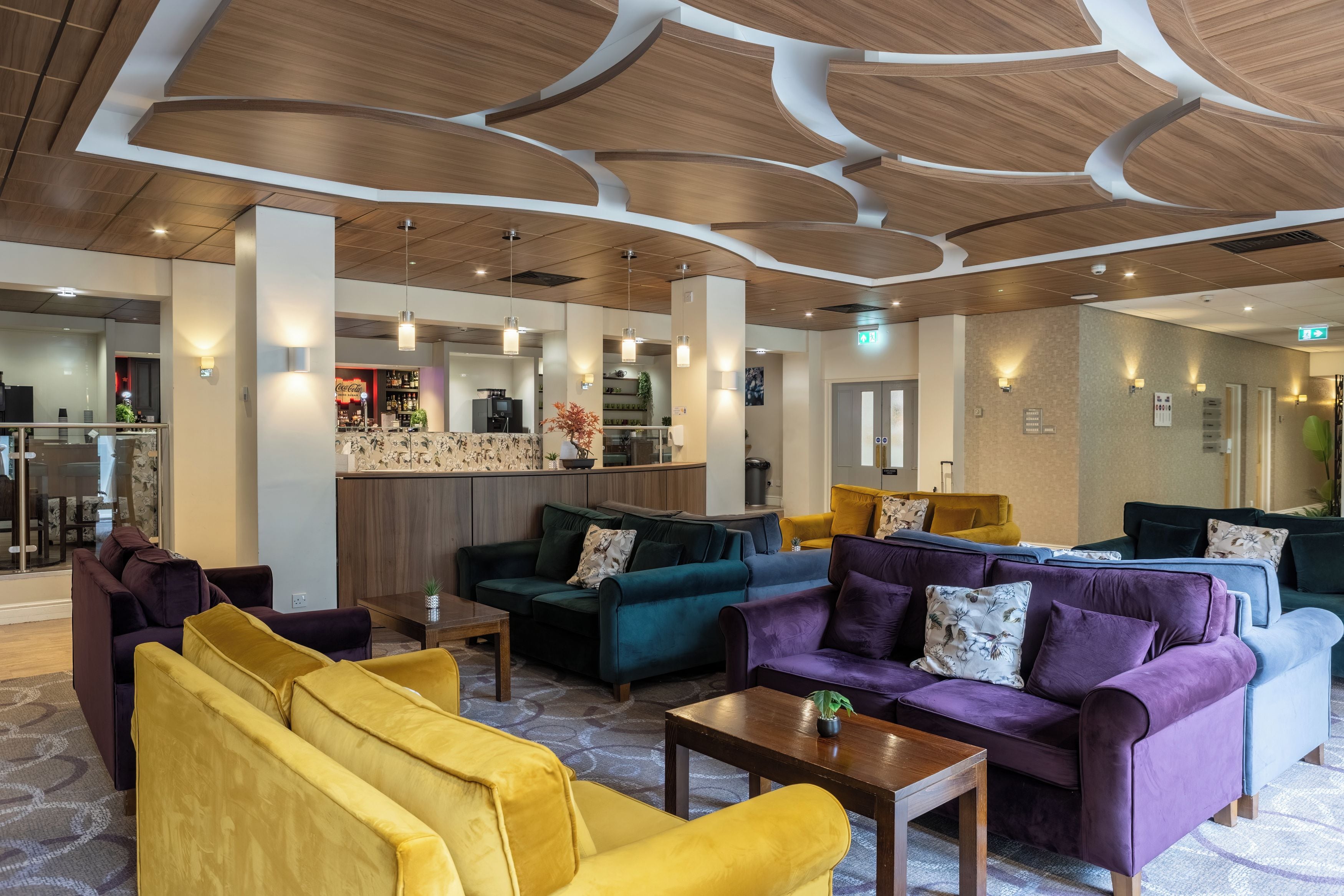 Una hall moderna con divani, un'area bar e un soffitto con pannelli in legno.