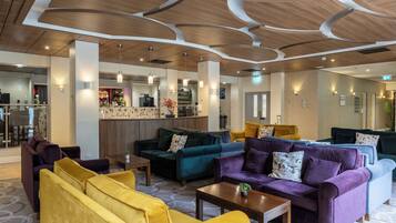 Una hall moderna con divani, un'area bar e un soffitto con pannelli in legno.