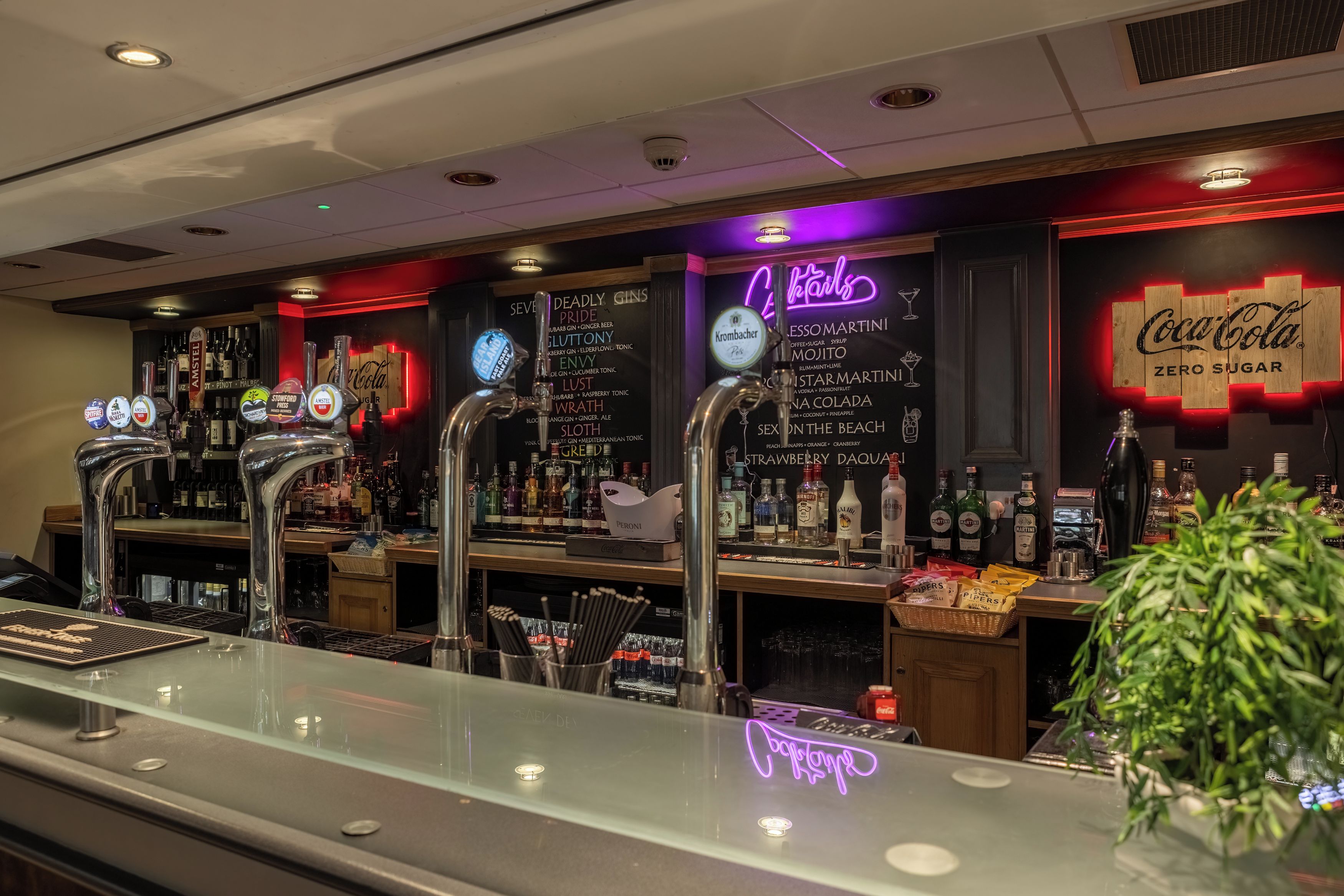 A bar area with multiple taps, a neon sign, and a Coca-Cola sign.