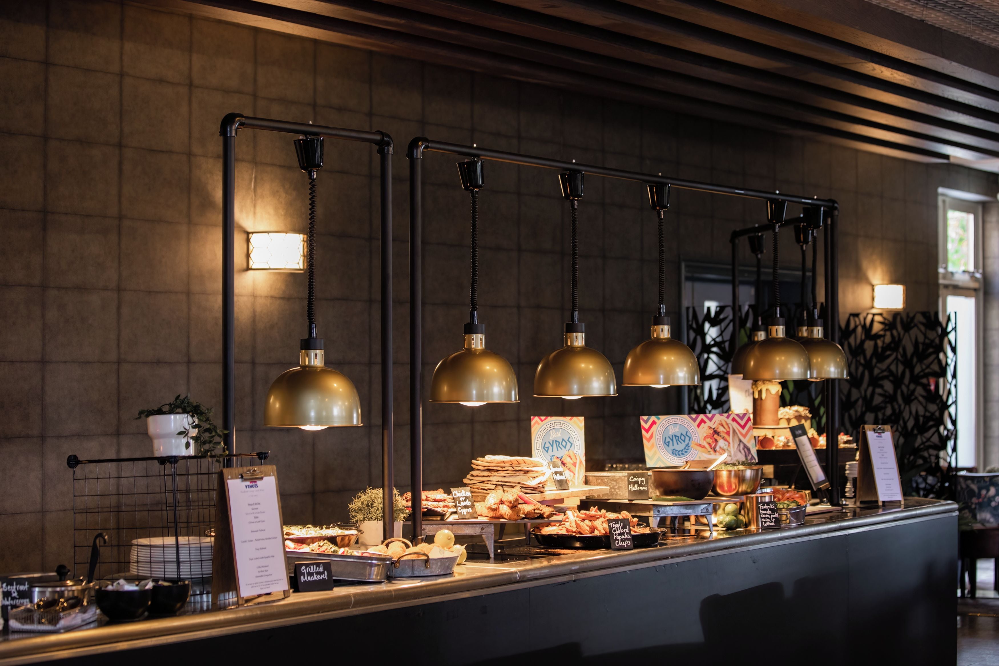 A buffet area with multiple food stations, overhead lighting, and menu boards.