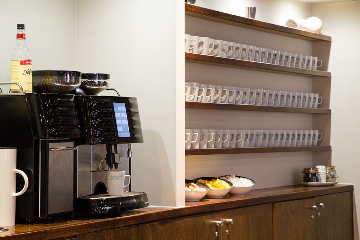 A coffee machine with a digital display, a bottle of water, and bowls of food on a counter.