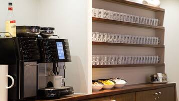 A coffee machine with a digital display, a bottle of water, and bowls of food on a counter.