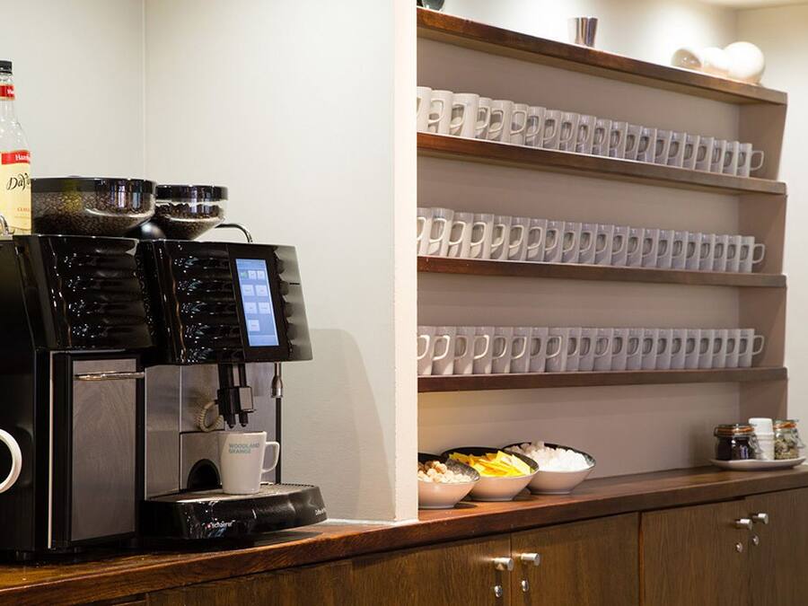 A coffee machine with a digital display, a bottle of water, and bowls of food on a counter.