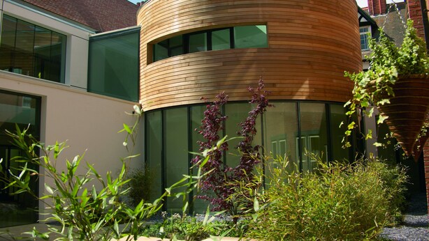 Een modern gebouw met een gebogen houten gevel en grote ramen.
