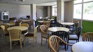 A dining area with multiple tables and chairs, a television, and a window providing natural light. - Le Relais de Port d'Albret - Hostel (Vieux-Boucau-les-Bains)
