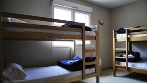 A room with two bunk beds, a window, and a radiator. - Le Relais de Port d'Albret - Hostel (Vieux-Boucau-les-Bains)