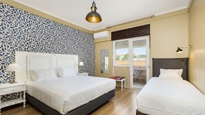 A hotel room with two beds, a patterned wall, a ceiling light, and a view through a glass door. - DOME Alvares Cabral (Lisbon)