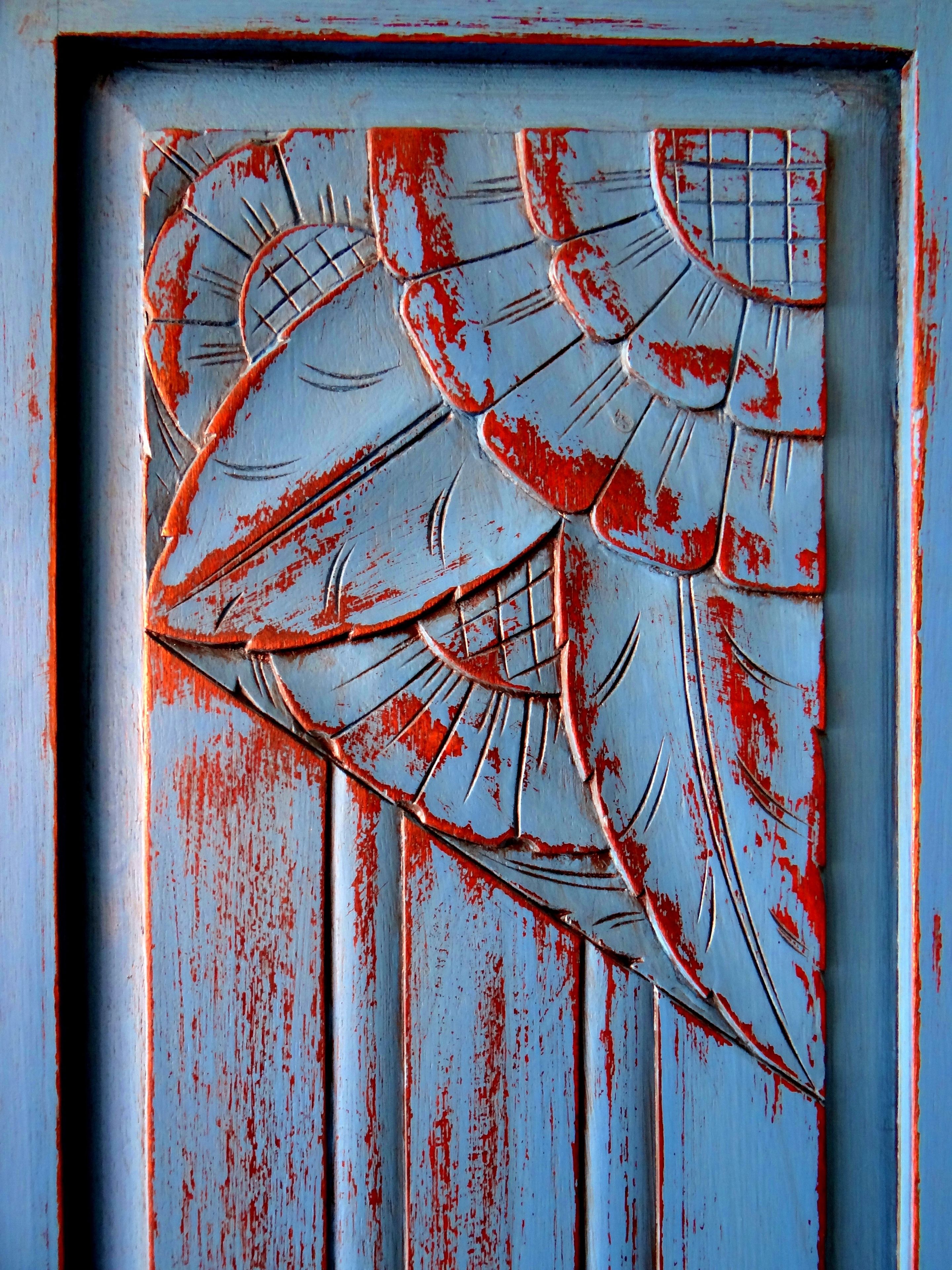 A door with a distressed red and white paint finish and a geometric pattern.