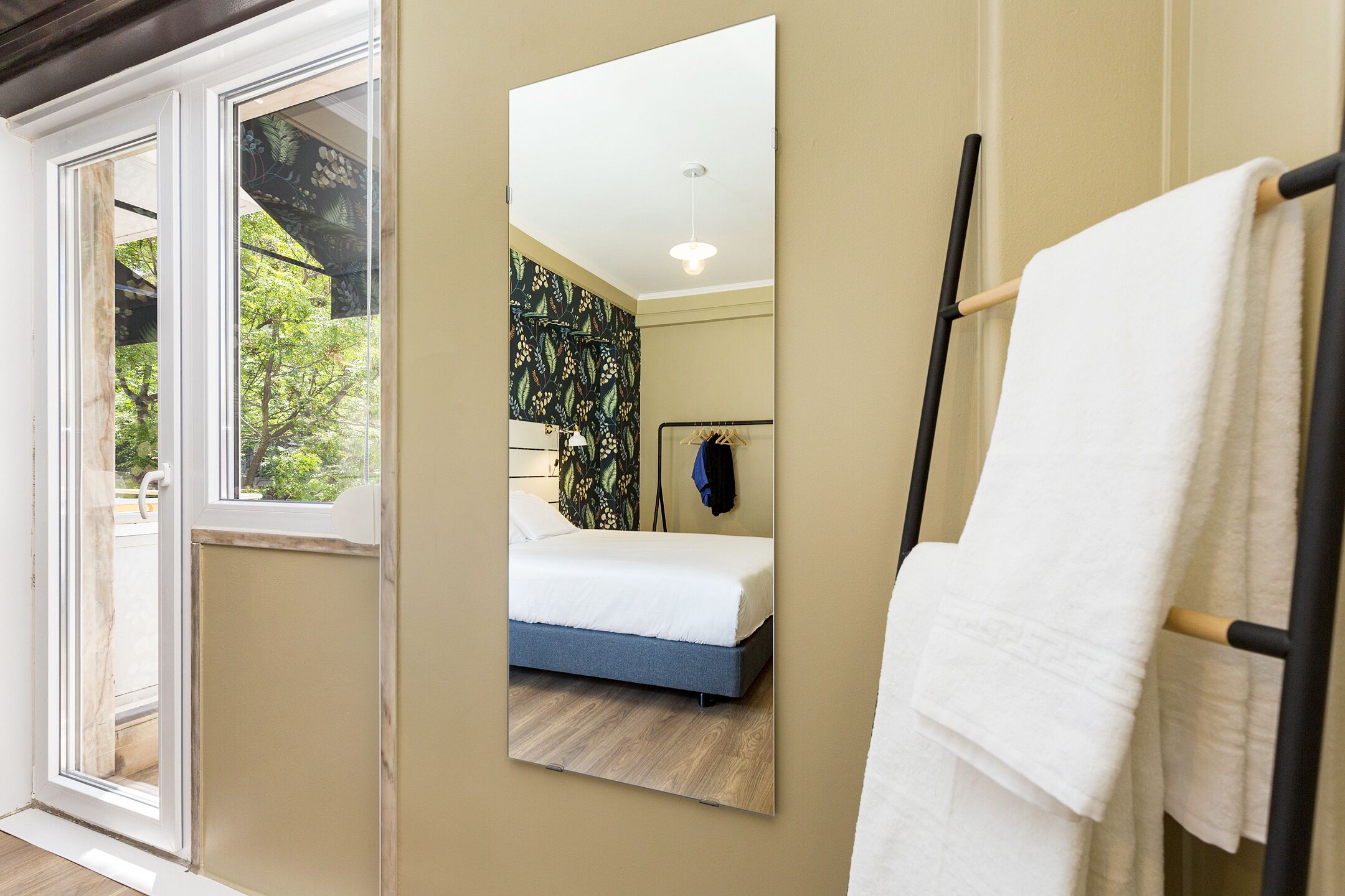 A bedroom with a bed, a mirror, and a towel rack.
