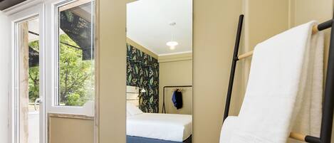 Un dormitorio con cama, espejo y toallero.