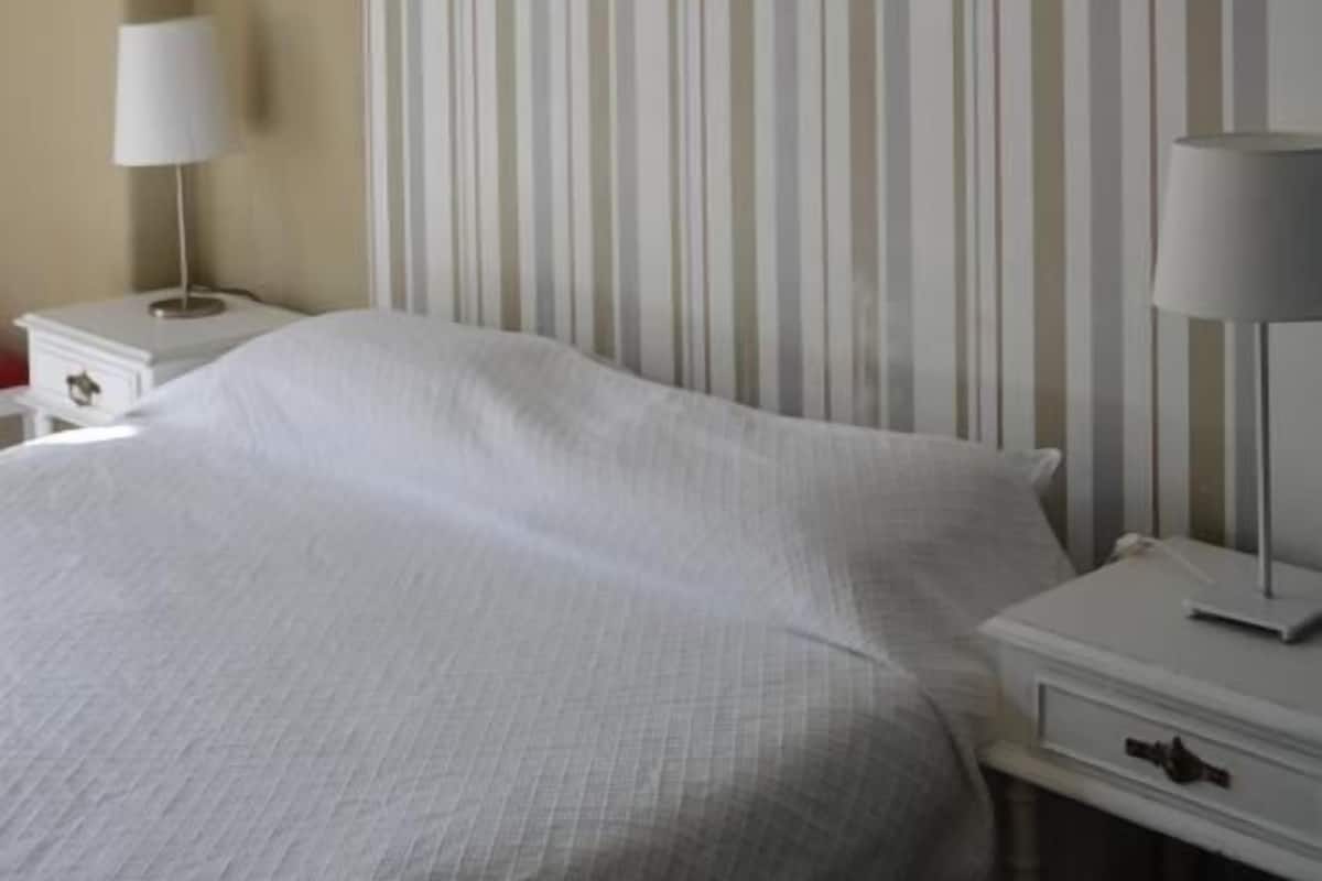 Una habitación de hotel con una cama grande, dos mesitas de noche con lámparas y una pared a rayas.