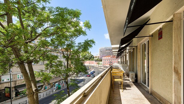 A balcony with a view of a tree-lined street and a building across the road. - DOME Alvares Cabral (Lisbon)