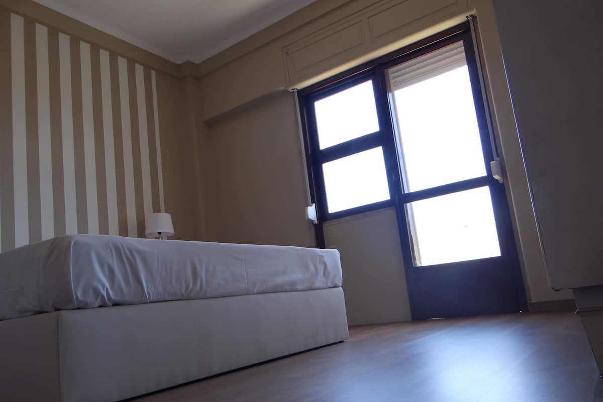 Un dormitorio con cama, ventana y puerta.