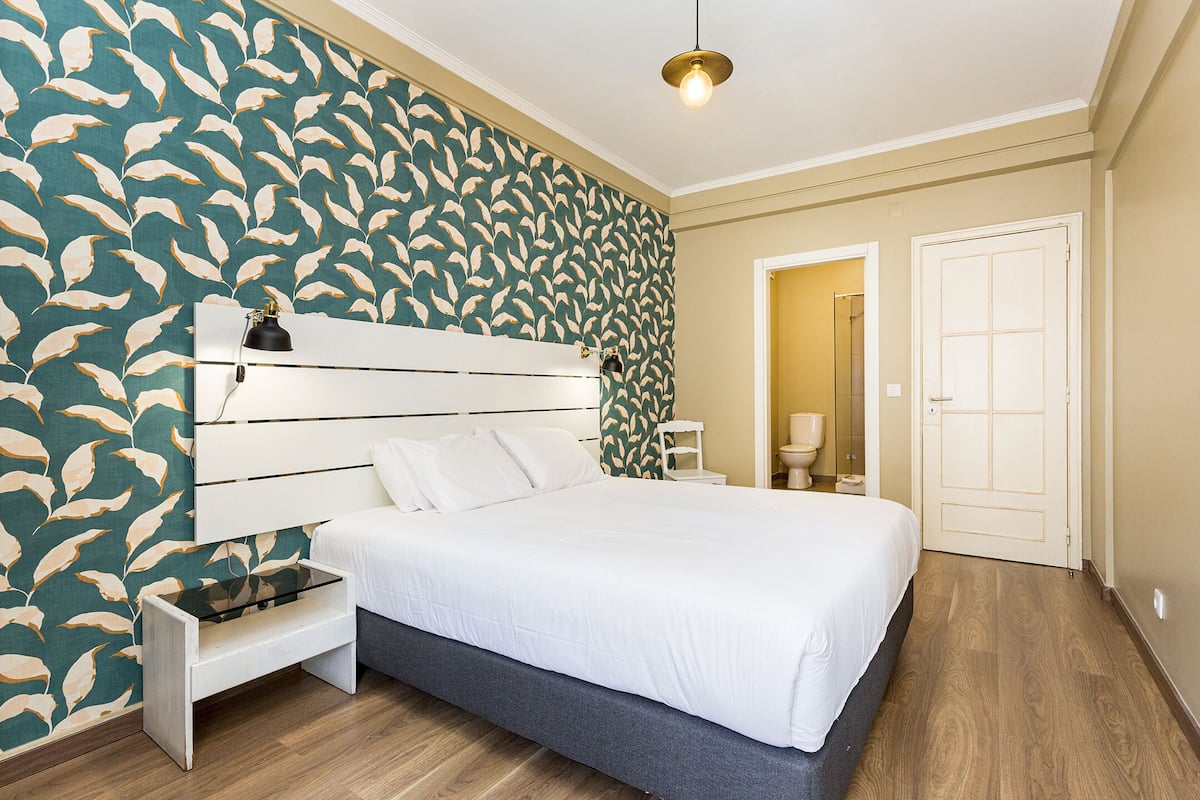 Un dormitorio con cama, mesita de noche y tocador.