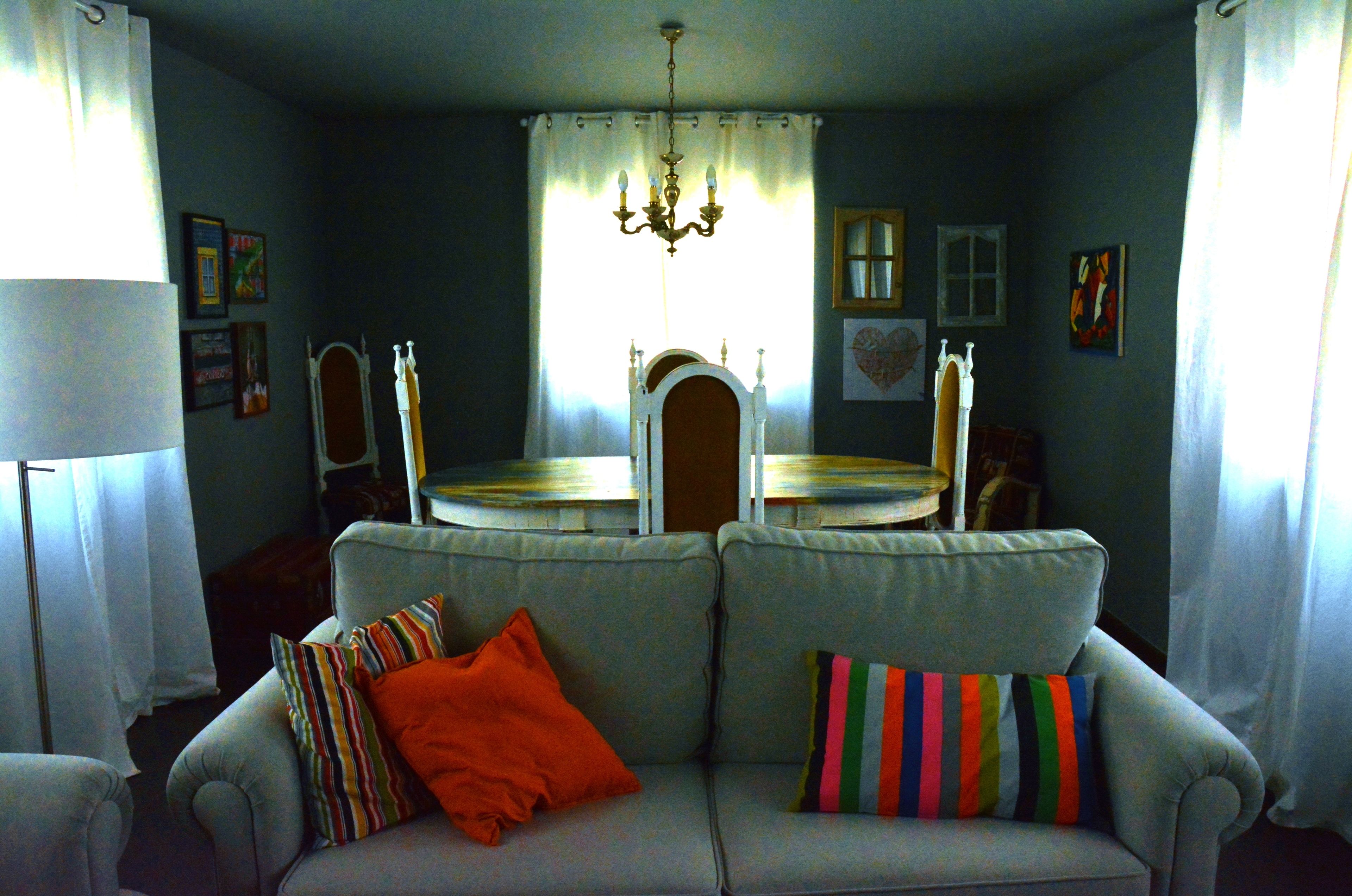 A living room with a sofa, a dining table, and a chandelier.