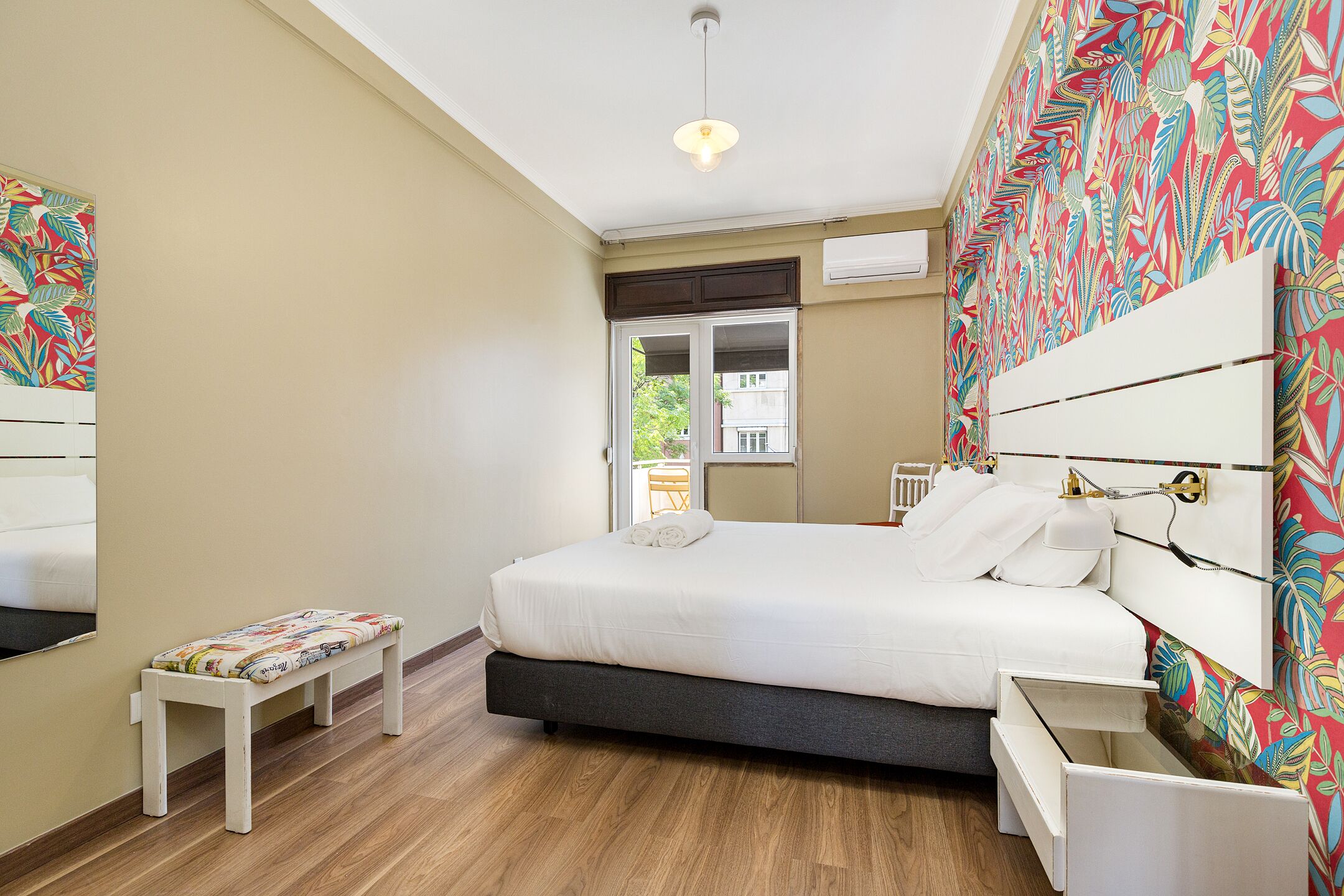 A bedroom with a bed, a bench, a bedside table, and a window.