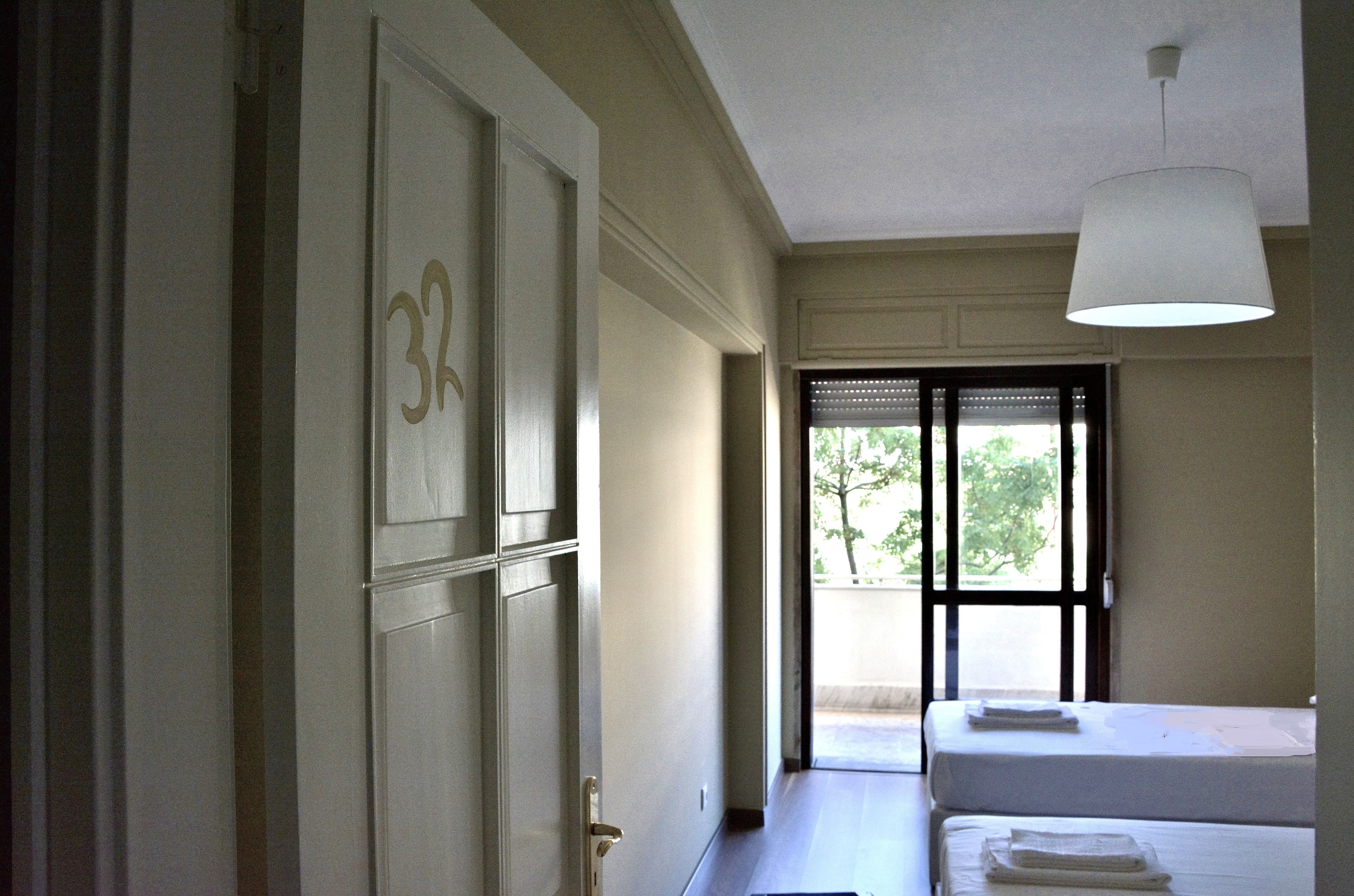 A hotel room with a bed, a door with the number 34, and a window with blinds.