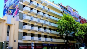 A multi-story building with balconies, storefronts, and a large billboard. - DOME Alvares Cabral (Lisbon)