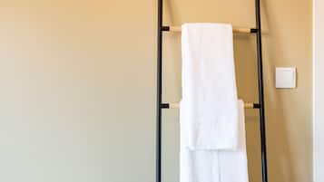 Um porta-toalhas com duas toalhas brancas em frente a uma parede bege.
