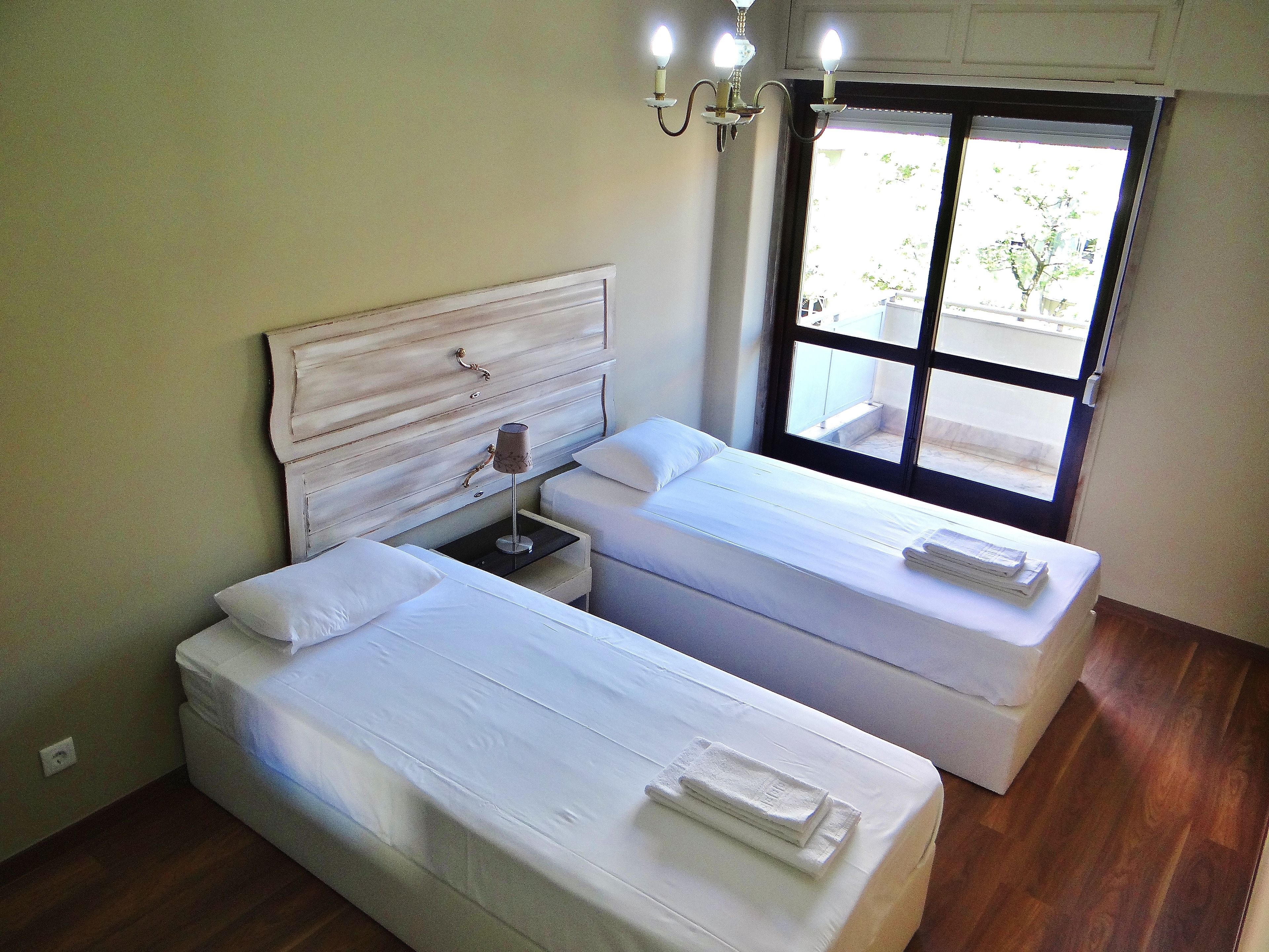 Un dormitorio con dos camas, una mesita de noche, una lámpara y una ventana con vistas.