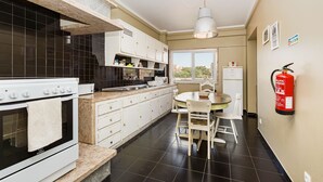 A modern kitchen with white cabinets, a white stove, and a dining area with a table and chairs. - DOME Alvares Cabral (Lisbon)