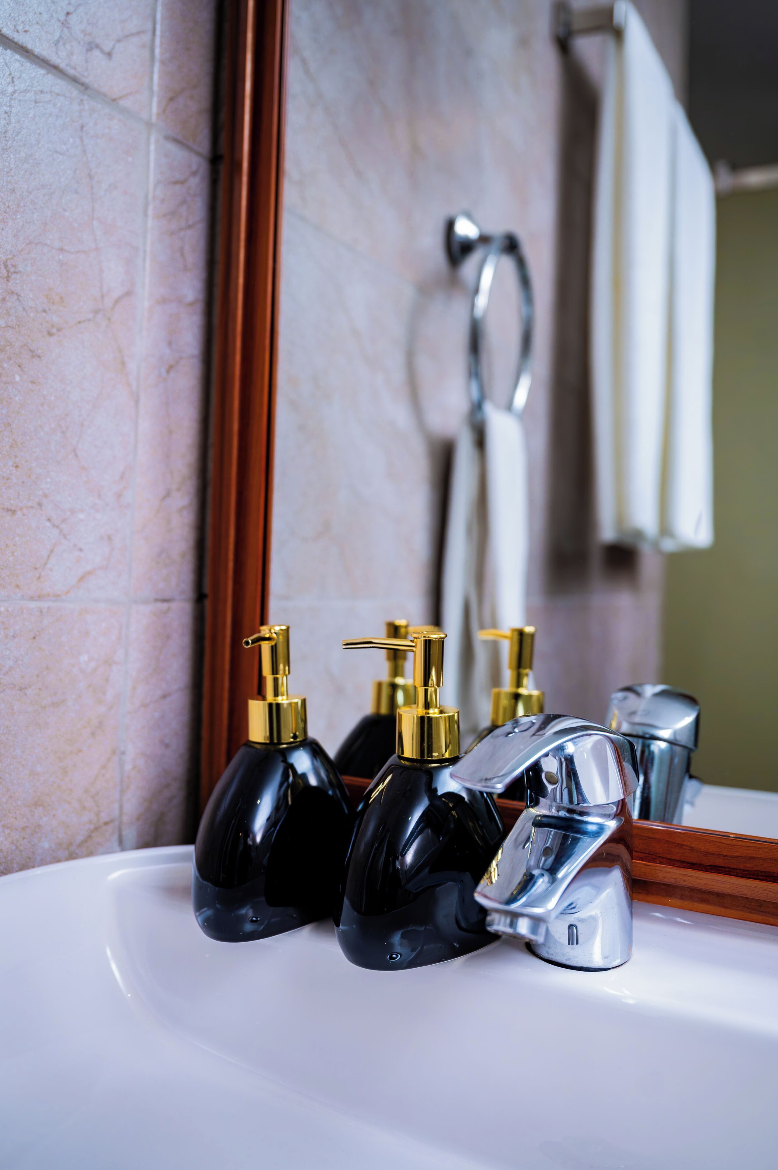 A bathroom with a white sink, chrome faucet, and black soap dispensers.