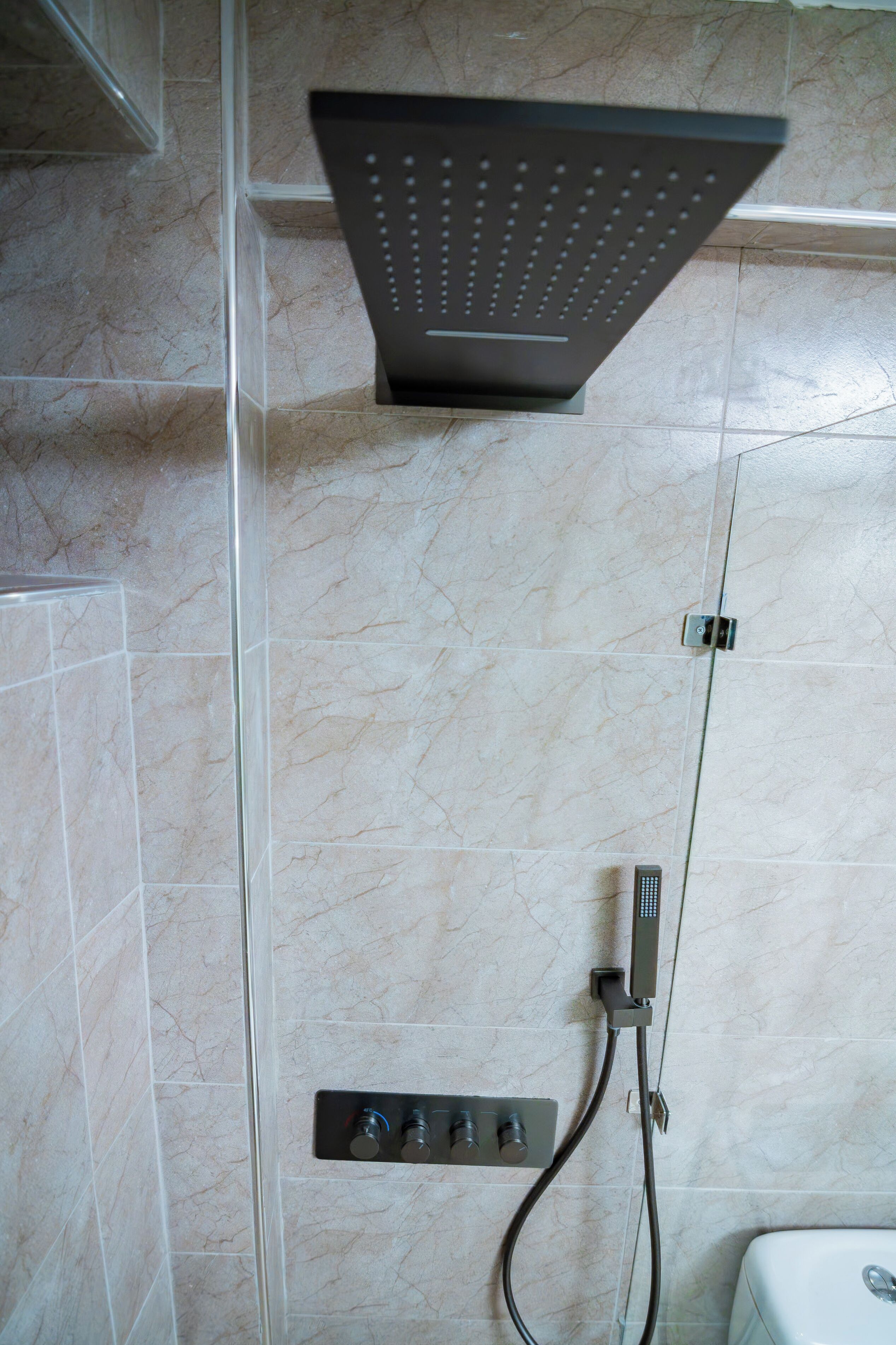 A shower with a modern design, a control panel, and a wall-mounted faucet.