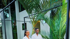A modern building with a glass facade, a metal balcony railing, and lush greenery. - Green Mountain Hotel (Arusha)