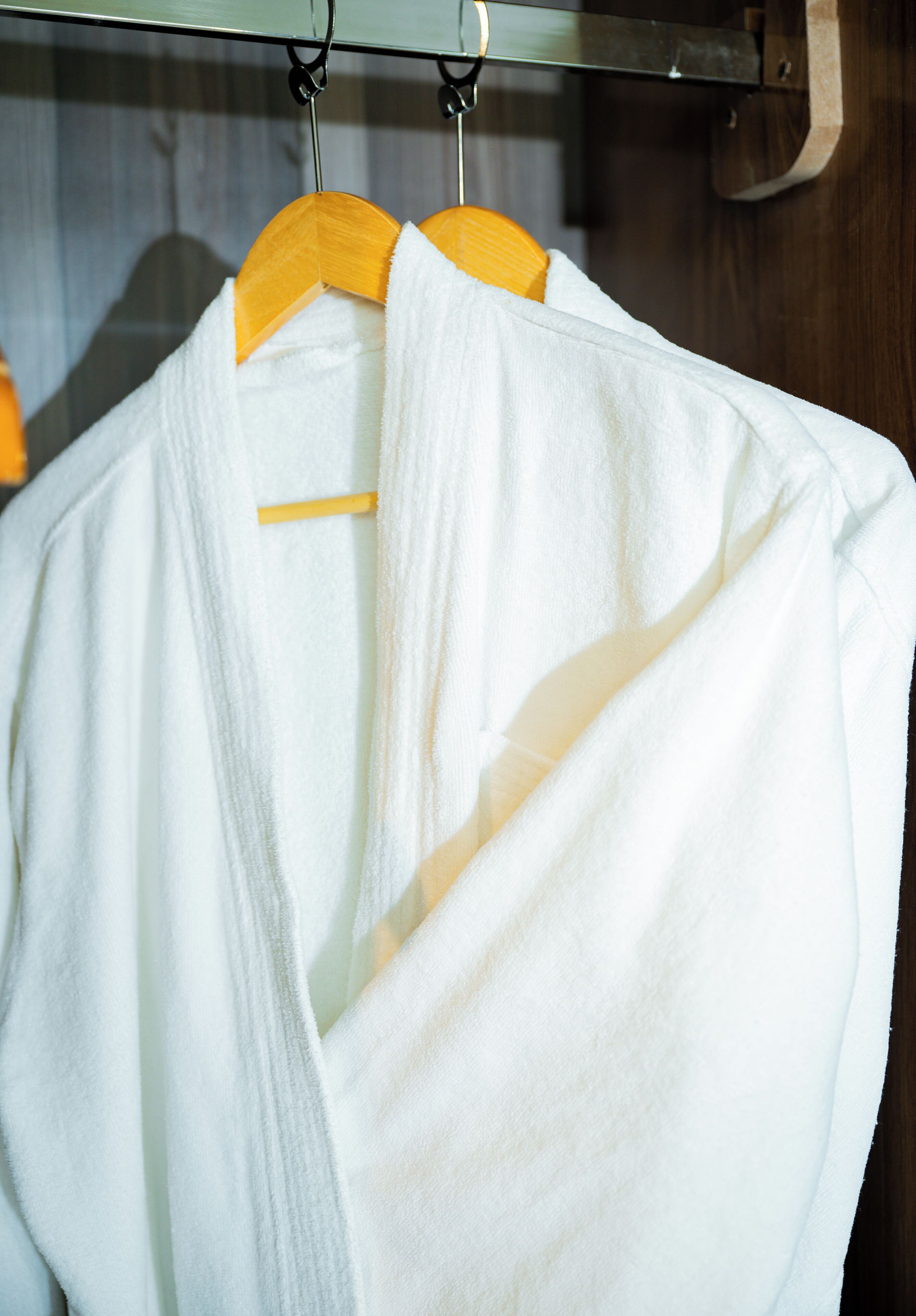 A white robe hanging on a wooden hanger.