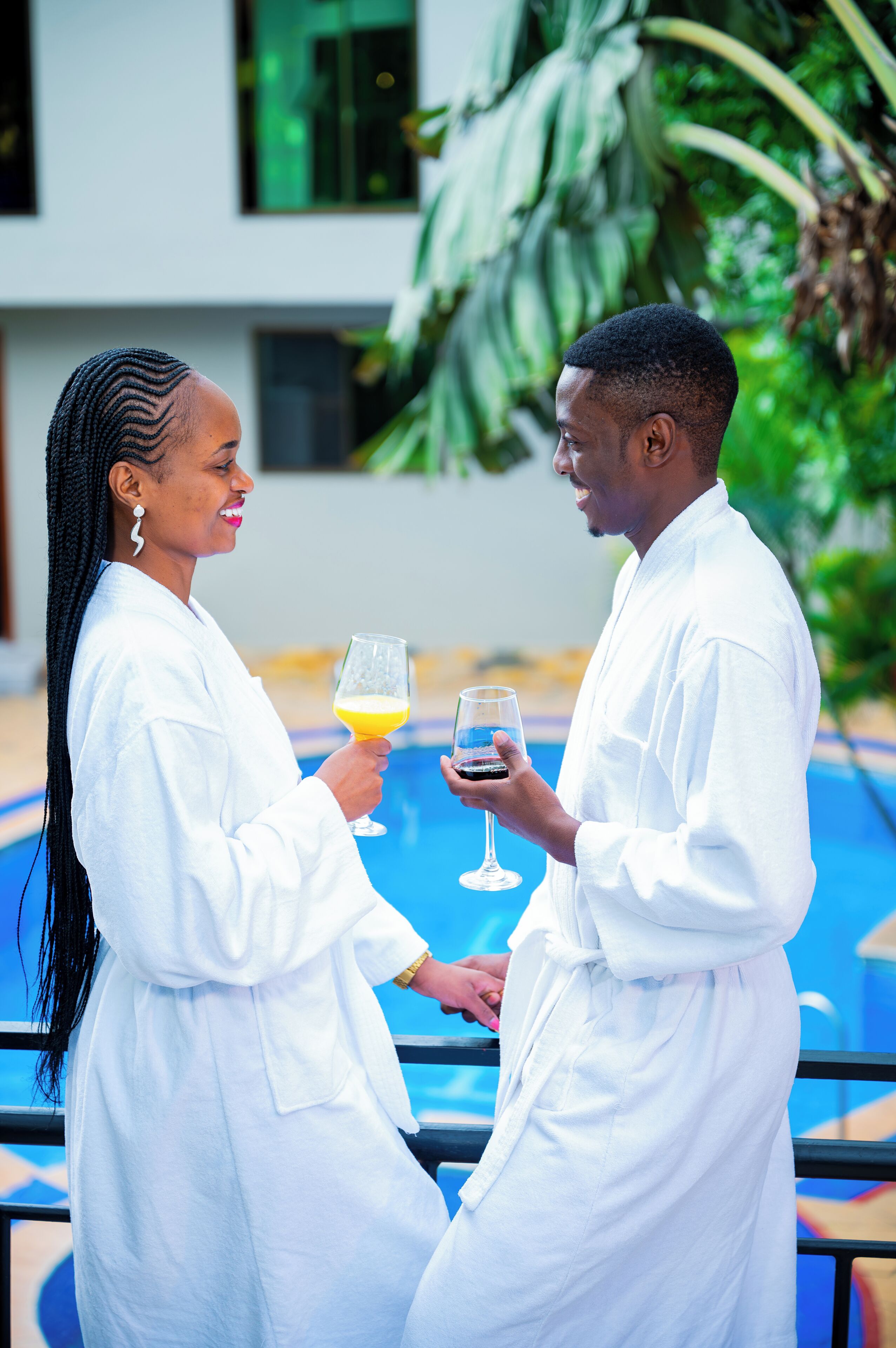 Two people in white robes by a pool with a modern building in the background.
