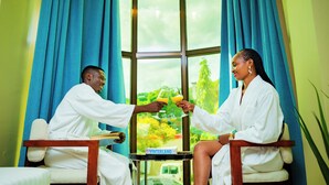 Two individuals seated in a room with a large window, a table with a book, and a VINTERLAND sign. - Green Mountain Hotel (Arusha)