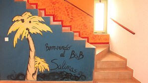A staircase with a palm tree mural and the text "Bem-vindo al B&B Salinas".