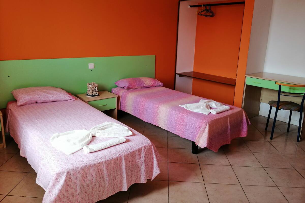 Una habitación con dos camas, un escritorio y una silla.