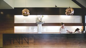 A hotel reception desk with a wooden panel design and a large vase of flowers.