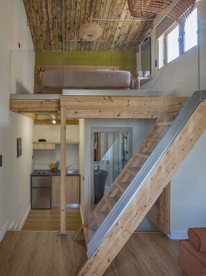 A loft bedroom with a bunk bed, a kitchen area, and a staircase.