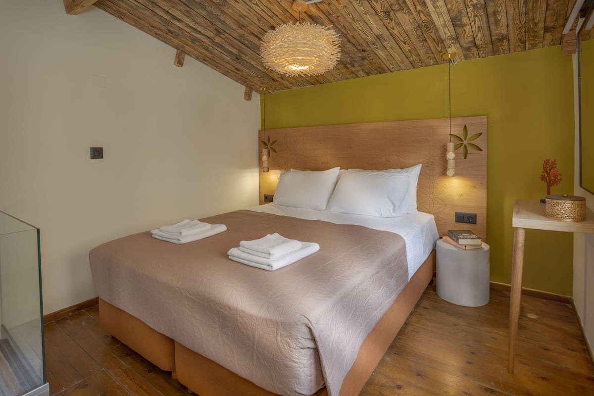 A neatly made bed with white linens, a wooden headboard, and a bedside table with a book and a decorative item.