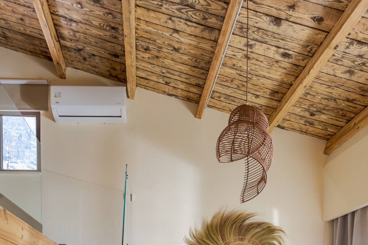 A modern interior with a wooden staircase, a sofa, and a decorative mirror.
