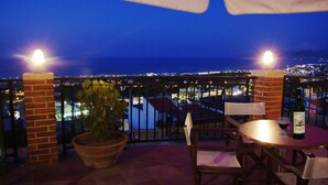 Una terrazza con tavolo, sedie, una pianta in vaso e una bottiglia di vino.