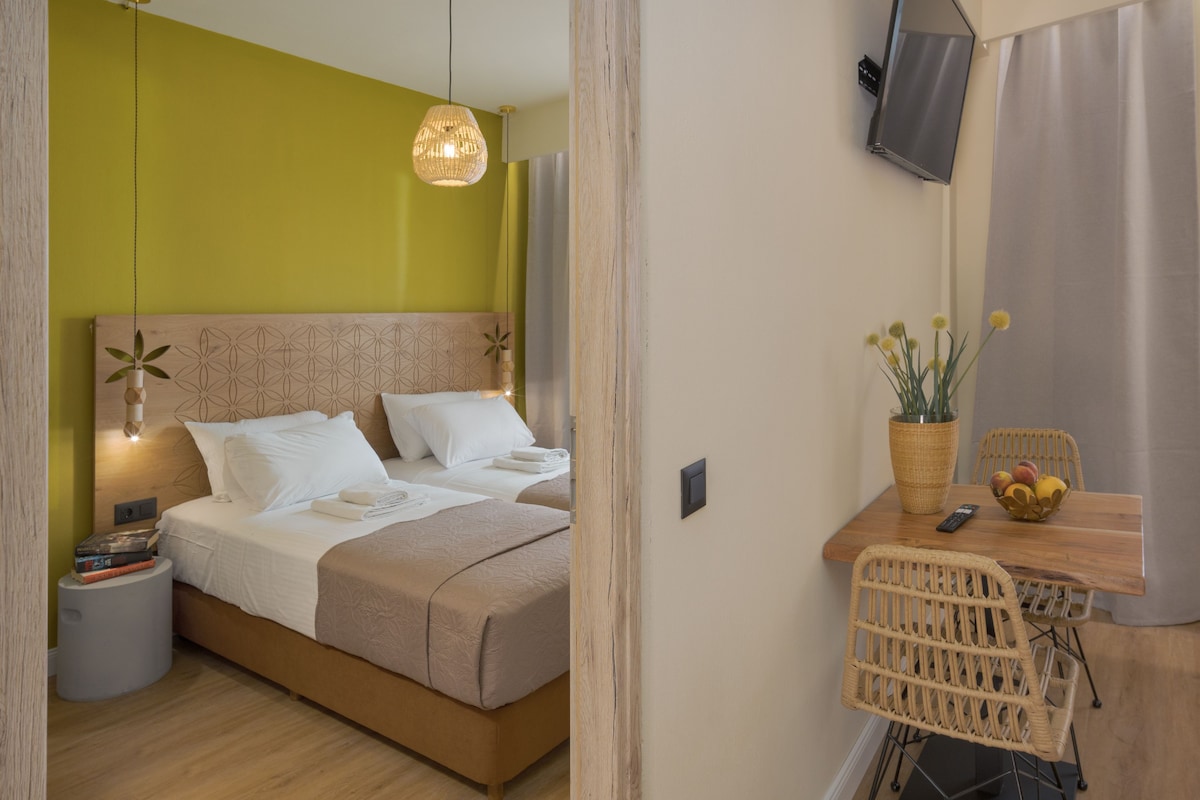 A hotel room with a bed, bedside table, lamp, and a small desk with a chair.