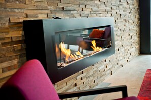 Une cheminée moderne avec une façade en verre, placée contre un mur en bois.