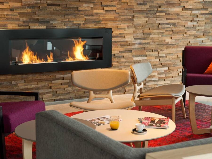 A modern lounge area with a fireplace, comfortable seating, and a small table with a drink and magazine.