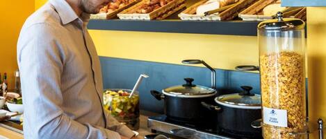 A buffet setup with various food items and a person serving.